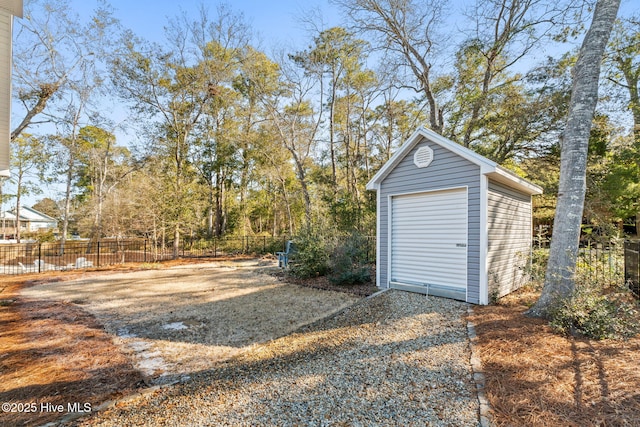 detached garage with gravel driveway, fence, and a storage shed