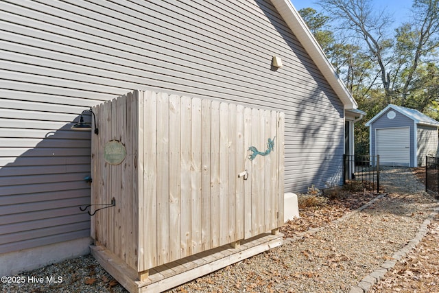 view of side of home featuring fence and an outbuilding