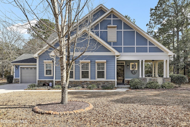 view of front facade with a garage, stone siding, a porch, and concrete driveway