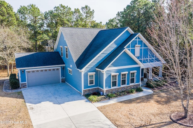 view of front of house with a garage, stone siding, roof with shingles, and driveway