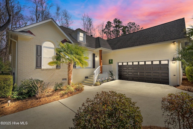 view of front facade with brick siding, roof with shingles, a garage, crawl space, and driveway