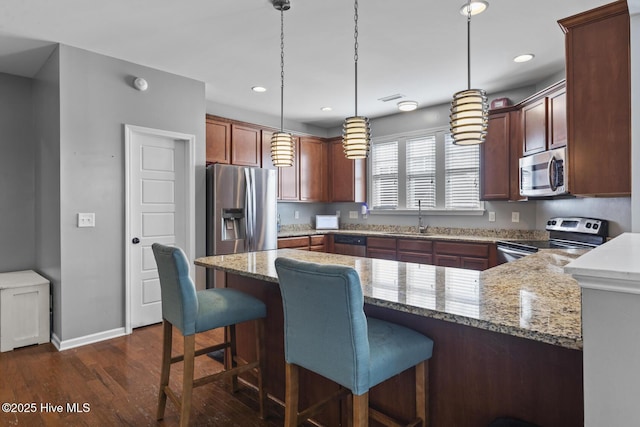 128 Pamlico Dr, Holly Ridge, NC 28445 - kitchen with stainless steel appliances, dark wood-type flooring, a peninsula, a sink, and hanging light fixtures