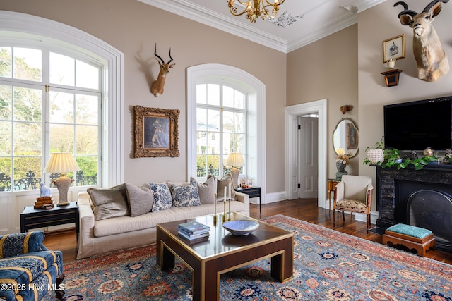 living room with an inviting chandelier, ornamental molding, a wealth of natural light, and dark wood-style flooring