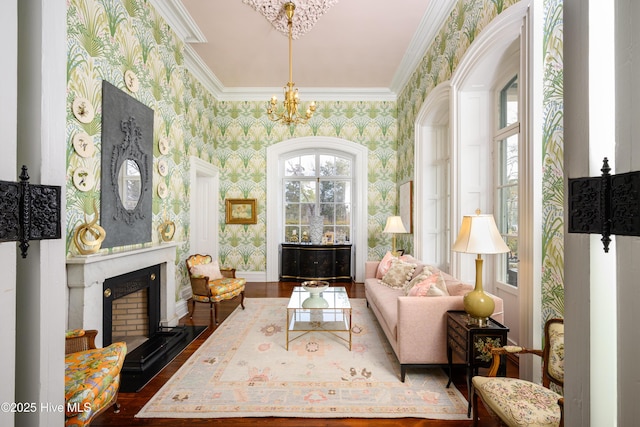 sitting room featuring wallpapered walls, baseboards, crown molding, a fireplace, and a chandelier