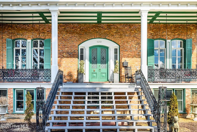 view of exterior entry with covered porch and brick siding