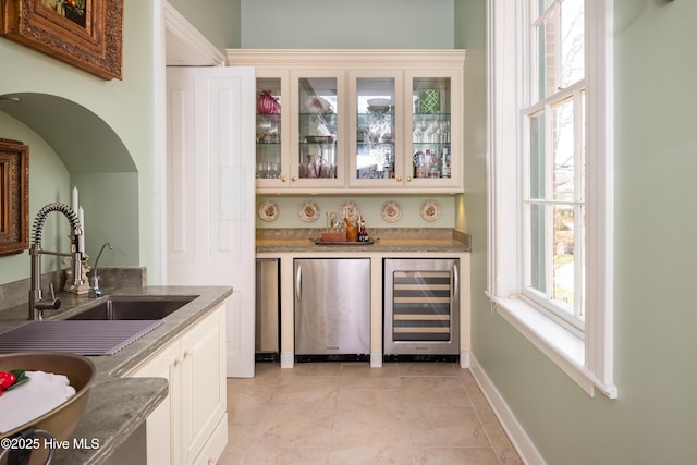 bar with wine cooler, refrigerator, bar area, a sink, and light tile patterned flooring