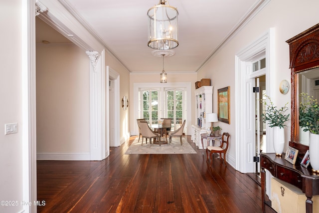 unfurnished dining area with dark wood-style floors, crown molding, baseboards, and a notable chandelier