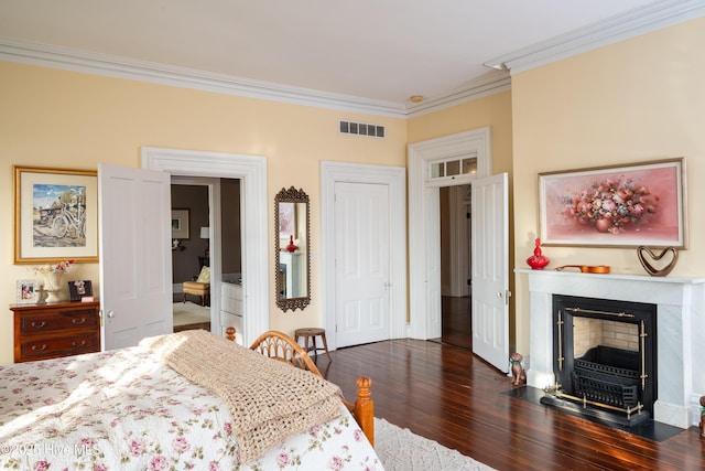 bedroom featuring dark wood-style floors, a fireplace with flush hearth, visible vents, and crown molding