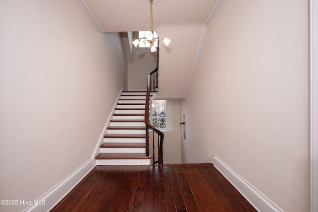 stairs with a notable chandelier, baseboards, crown molding, and wood finished floors