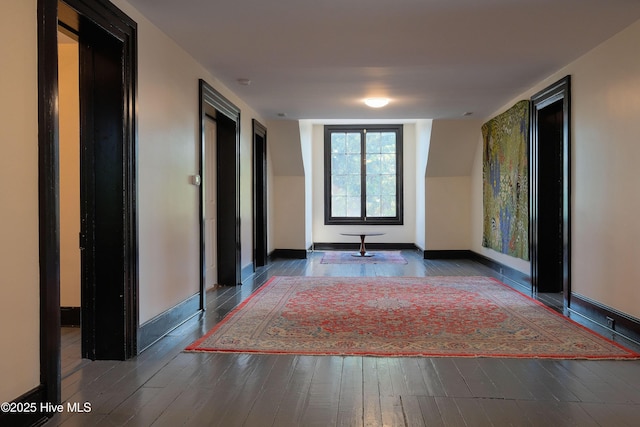 corridor with baseboards and wood finished floors