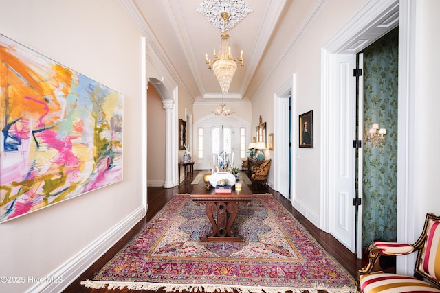 hallway with arched walkways, french doors, crown molding, dark wood-type flooring, and a chandelier