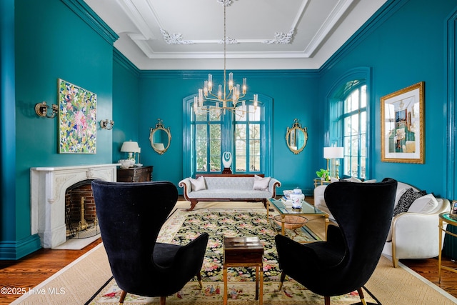 living room with a fireplace, a chandelier, wood finished floors, and ornamental molding