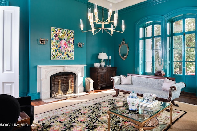 interior space with ornamental molding, a fireplace, wood finished floors, and an inviting chandelier