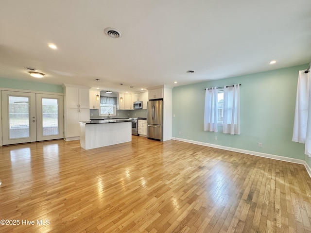 unfurnished living room with light wood-style floors, baseboards, visible vents, and recessed lighting