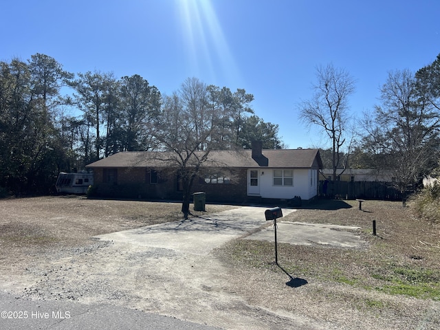 ranch-style house featuring fence and dirt driveway