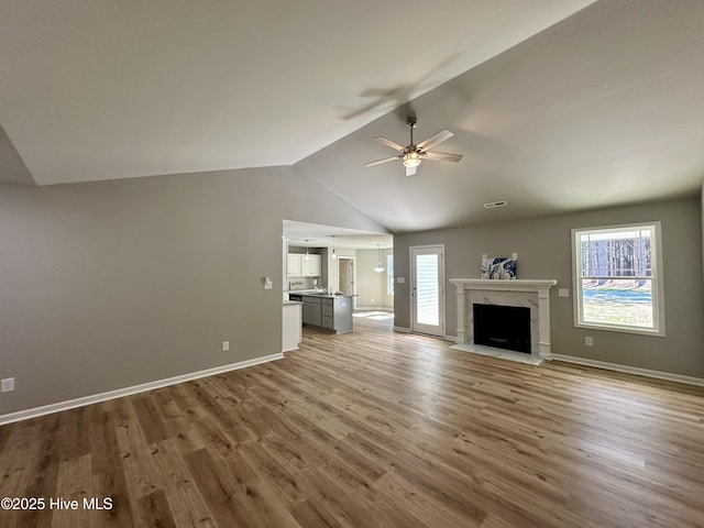 unfurnished living room with wood finished floors, a fireplace, a wealth of natural light, and ceiling fan