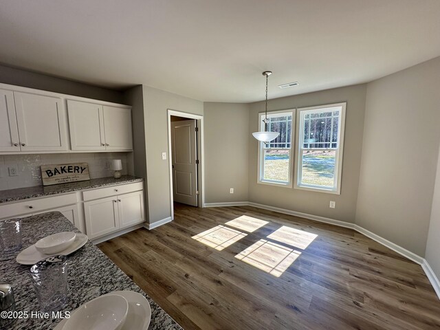 kitchen with white cabinetry, wood finished floors, backsplash, and stainless steel appliances