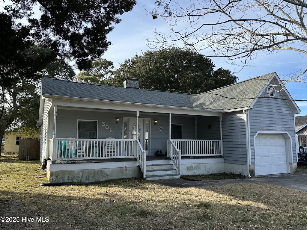 ranch-style house with a garage, covered porch, a chimney, and a front yard