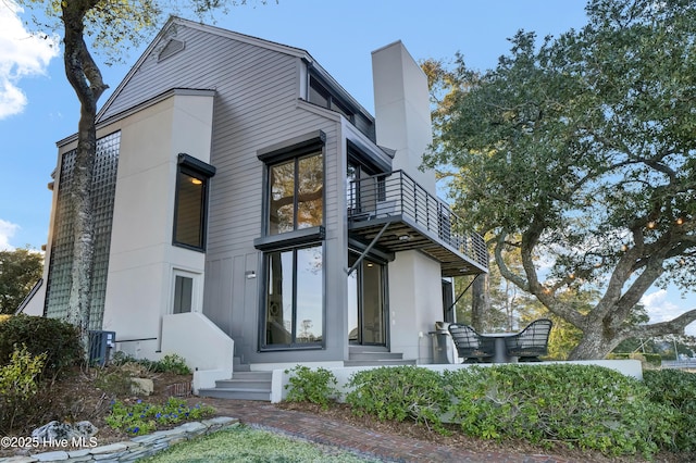 view of front of house with a chimney and a balcony