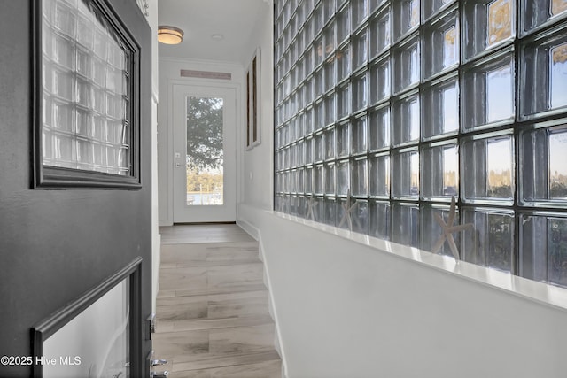 corridor featuring baseboards, wood finished floors, and crown molding