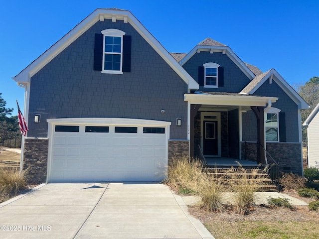 view of front of property featuring a garage, stone siding, covered porch, and concrete driveway