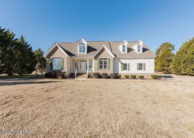 cape cod home featuring a front lawn