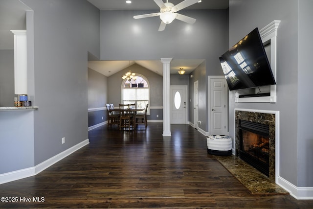 interior space with baseboards, a fireplace, wood finished floors, and ornate columns