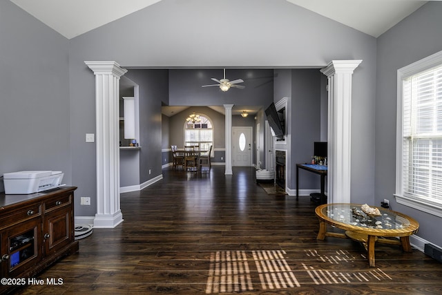 interior space with vaulted ceiling, baseboards, wood finished floors, and ornate columns