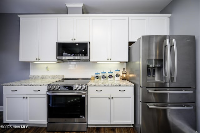 kitchen with light stone counters, white cabinetry, stainless steel appliances, and backsplash