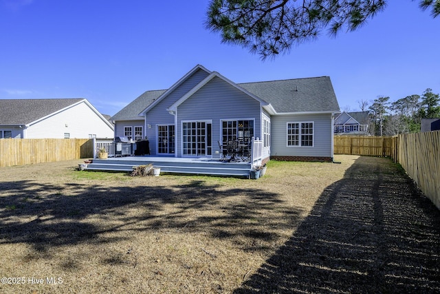 rear view of property with a fenced backyard, a deck, and roof with shingles