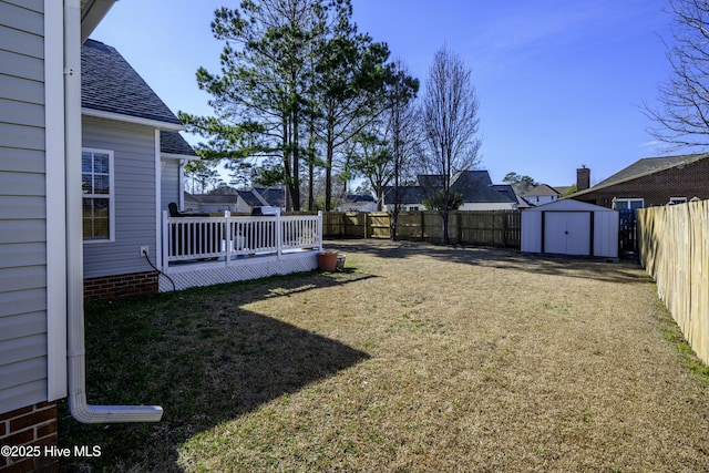 view of yard featuring a shed, an outdoor structure, a fenced backyard, and a wooden deck