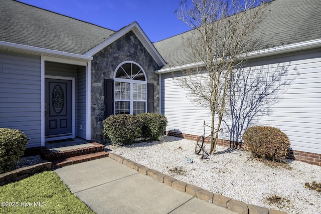 property entrance featuring stone siding and a shingled roof