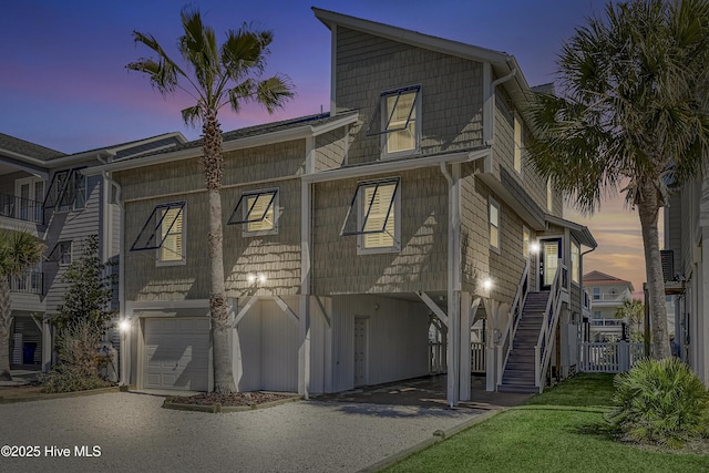 view of front of property with an attached garage, stairs, and aphalt driveway