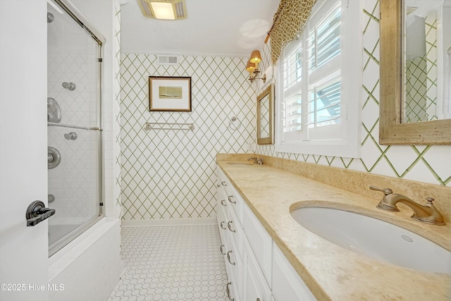 full bathroom with a sink, visible vents, tiled shower / bath, wallpapered walls, and crown molding