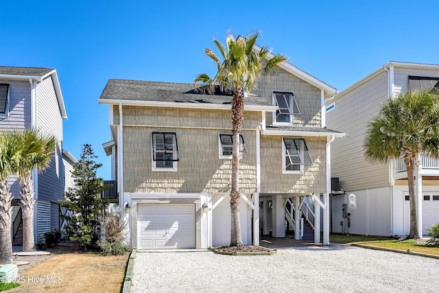 coastal inspired home with a carport, gravel driveway, roof with shingles, and stairway