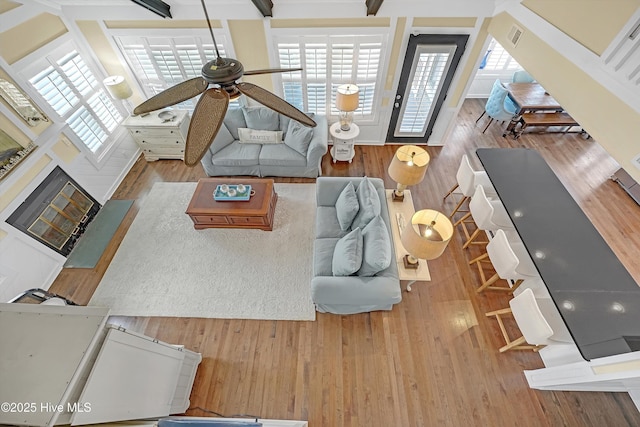 living room featuring visible vents, a fireplace, wood finished floors, and a ceiling fan