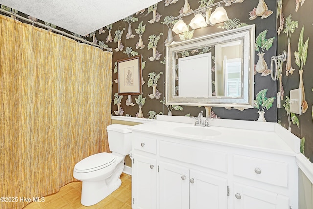 full bath featuring a textured ceiling, toilet, vanity, tile patterned floors, and wallpapered walls