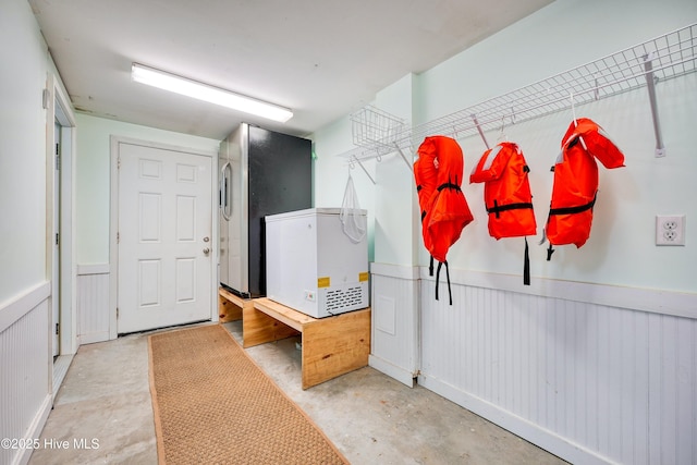 mudroom with unfinished concrete flooring and wainscoting