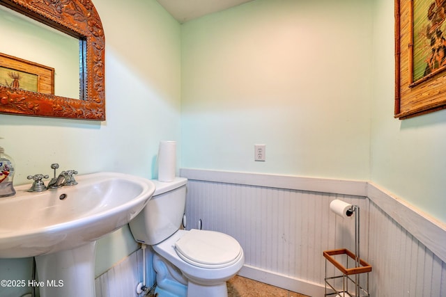 bathroom featuring a wainscoted wall, a sink, and toilet