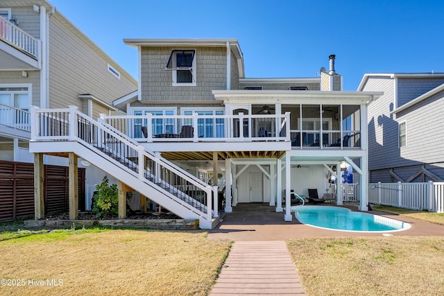 back of property featuring an outdoor pool, a lawn, a sunroom, a chimney, and stairs