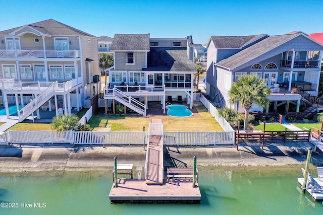 rear view of property with stairs, a deck with water view, a fenced backyard, and a residential view