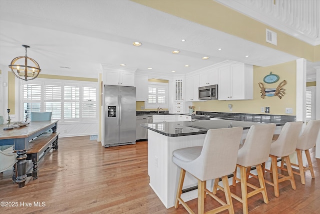 kitchen with visible vents, white cabinets, dark countertops, a peninsula, and stainless steel appliances