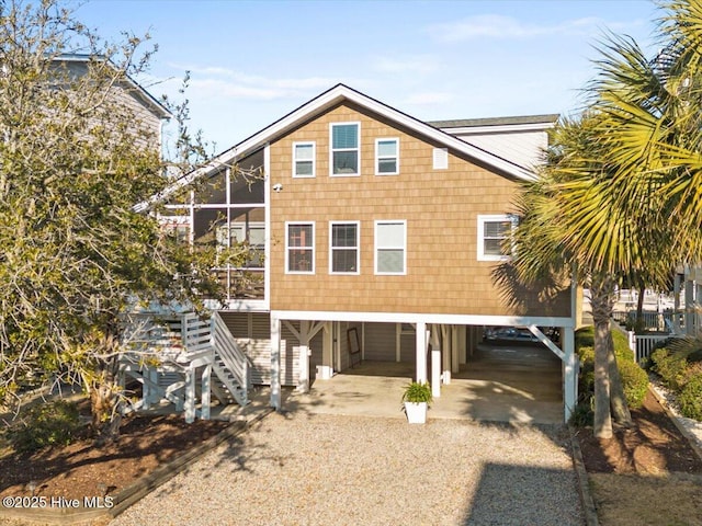 view of front of house with gravel driveway, stairs, and a carport