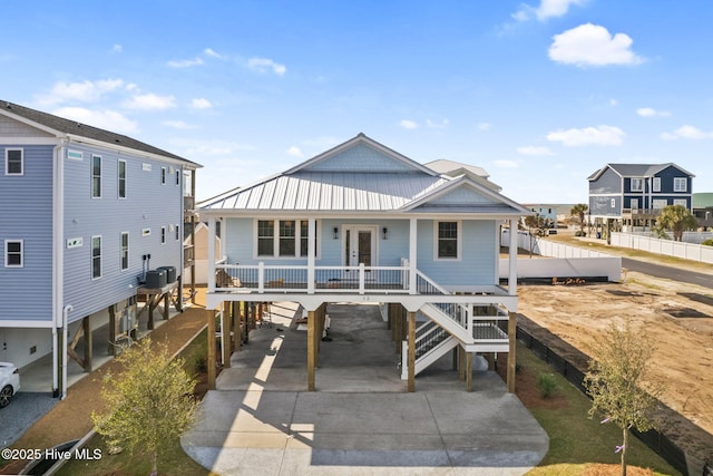 coastal home with driveway, covered porch, stairs, french doors, and a carport