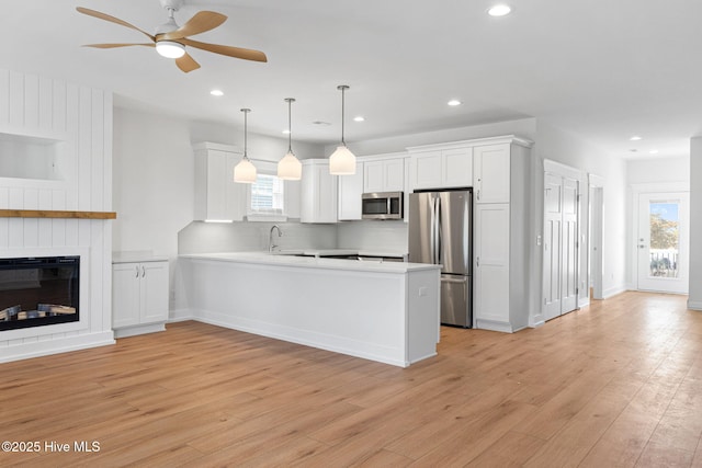 kitchen featuring appliances with stainless steel finishes, light wood-type flooring, a wealth of natural light, and white cabinetry