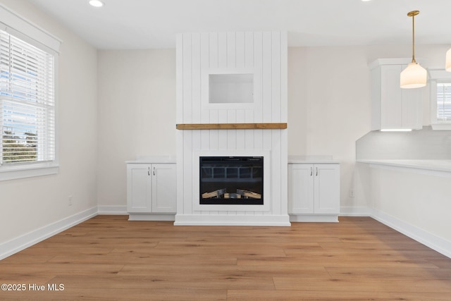 unfurnished living room featuring recessed lighting, baseboards, a fireplace, and light wood finished floors