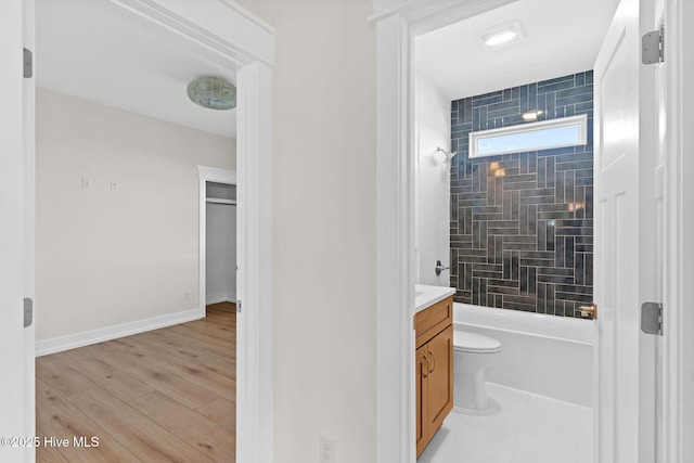 bathroom featuring toilet, shower / bath combination, wood finished floors, vanity, and baseboards