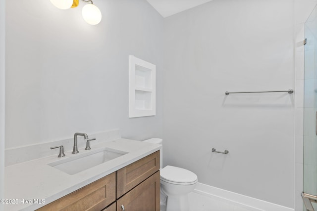 bathroom featuring a shower with door, vanity, and toilet