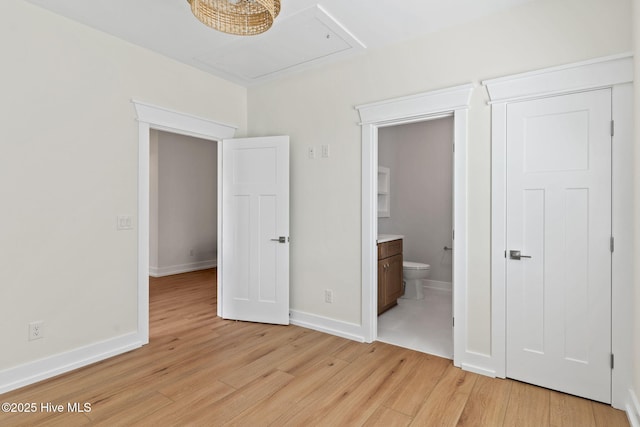 unfurnished bedroom featuring light wood-style floors, connected bathroom, and baseboards