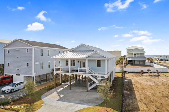 view of front facade with concrete driveway, metal roof, stairs, a porch, and a carport